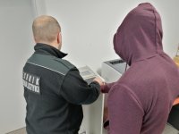 technik kryminalistyki pobiera odciski palców od zatrzymanego
