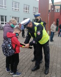 policjanci rozdają uczniom elementy odblaskowe