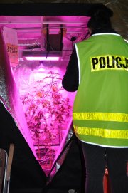 policjantka ubrana w kamizelkę odblaskową z napisem policja przy szafie przygotowanej do produkcji nielegalnych środków