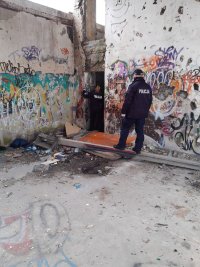 policjanci podczas sprawdzania opuszczonego budynku, policjantka zagląda do pomieszczeń w celu odnalezienia osób potrzebujących pomocy