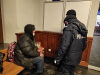 policjanci rozmawiają z osobą bezdomną, która ogrzewała się na terenie dworca PKP