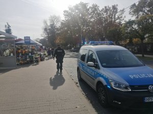 na zdjęciu widać policyjny radiowóz i policjanta podczas patrolowania rejonu przy piotrkowskiej nekropolii
