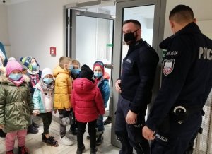 policjanci oprowadzają grupę dzieci z piotrkowskiego przedszkola po terenie Komendy Miejskiej Policji w Piotrkowie Trybunalskim