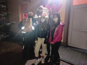 policjant, naczelnik OSP Rozprza oraz 3 dziewczyny z Młodzieżowej Drużyny Pożarniczej w Rozprzy przed wejściem do Domu Dziecka
