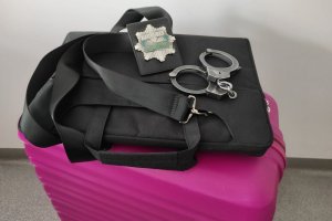 walizka, a na niej laptop w etui, kajdanki i odznaka policyjna