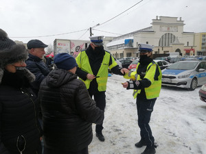 policjant i policjantka z Wydziału Ruchu Drogowego piotrkowskiej komendy Policji rozmawiają z seniorami o bezpieczeństwie na miejskim targowisku