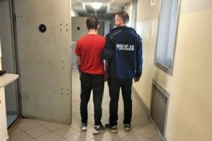 zatrzymany z policjantem, stoją tyłem w korytarzu