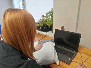 na zdjęciu widać kobietę siedzącą przy biurku, na którym znajduje się laptop