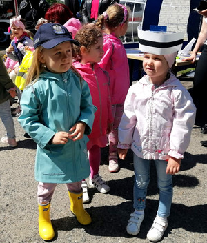 na zdjęciu dziewczynki z grupy przedszkolnej, jedna dziewczynka ma na głowie policyjną czapkę a druga pielęgniarski czepek . Zdjęcie zrobione podczas pikniku z okazji Dnia Dziecka