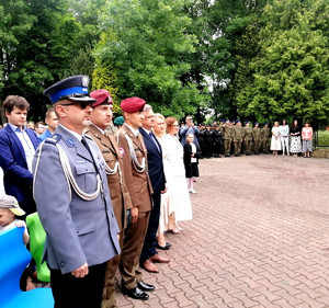 Komendant Rękawiecki oraz zaproszeni goście na dziedzińcu budynku szkoły w Bujnach. W tle młodzież klas mundurowych