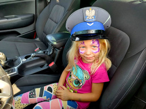 dziewczynka w policyjnym radiowozie z policyjną czapką