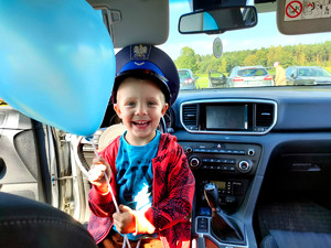 chłopiec w radiowozie w policyjnej czapce