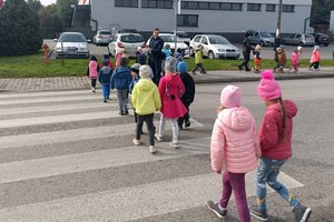 grupa przedszkolaków przechodzi przez przejście dla pieszych pod okiem policyjnego profilaktyka
