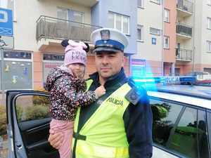 policjant trzyma na rękach dziewczynkę podczas wizyty w przedszkolu