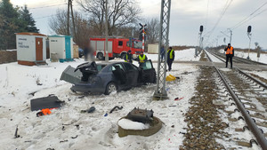 Policjanci pracują na miejscu wypadku w wyniku, którego doszło do zderzenia samochodu osobowego z pociągiem