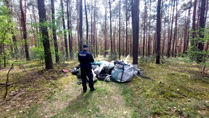 policjant przy śmieciach odnalezionych w lesie
