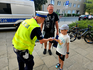 Policjanci wręczający odblaski wraz dziećmi.