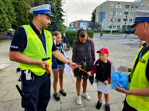 Policjanci wręczający odblaski wraz dziećmi.