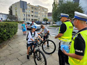 Policjanci wręczający odblaski wraz dziećmi.