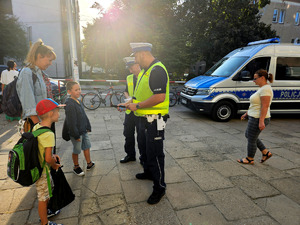 Policjanci wręczający odblaski wraz dziećmi.