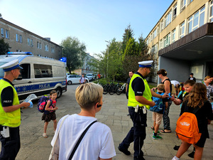 Policjanci wręczający odblaski wraz dziećmi.