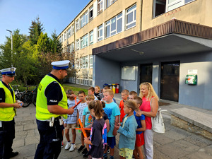 Policjanci wręczający odblaski wraz dziećmi.