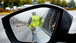 Policjant widoczny w lustrze samochodowym.