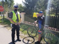 policjant przekazuje kamizelkę odblaskową rowerzyście