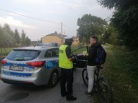 policjant rozmawia z rowerzystą o obowiązku noszenia odblasków