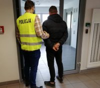 policjant prowadzi zatrzymanego przez korytarz
