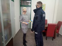 policjant przekazujący dyrekcji szkoły plakat