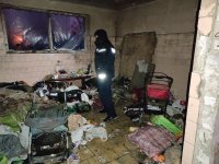 policjant w pustostanie sprawdzając czy nie przebywają tam osoby bezdomne, na podłodze widoczne opakowania po żywności, koce, kołdry,