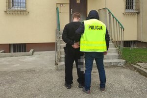 na zdjęciu policjant prowadzi zatrzymanego do policyjnego aresztu