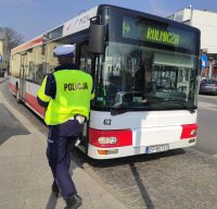 policjant idący w kierunku autobusu komunikacji miejskiej celem przeprowadzania kontroli