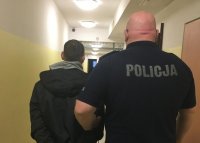 policjant z zatrzymanym w korytarzu pomieszczenia dla zatrzymanych