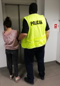 policjant prowadzi zatrzymaną do windy