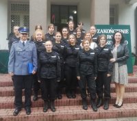 Zastępca Komendanta Miejskiego Policji w Piotrkowie Trybunalskim mł insp. Rafał Rękawiecki  stoi przed budynkiem z młodzieżą z klasy policyjnej i przedstawicielem dyrekcji  tej placówki oświatowej