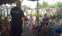 dzielnicowy w trakcie pogadanki rozmawia z dziećmi . Na zdjęciu widać policjanta stojącego przodem do siedzących dzieci