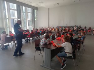 Aula piotrkowskiej komendy - dzielnicowi przeprowadza pogadankę z dziećmi na temat beczeństwa podczas wakacyjnego wypoczynku