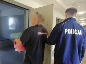 policjant prowadzi zatrzymanego do policyjnej celi