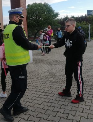 policjant o bezpieczeństwie w drodze do szkoły rozmawia z uczniem