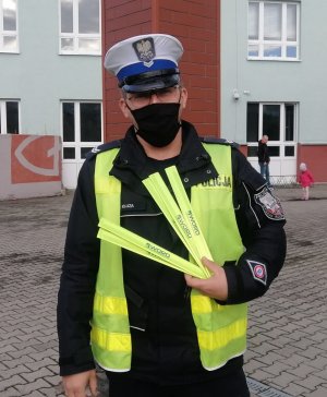 na zdjęciu policjant ruchu drogowego przygotowuje się do akcji profilaktycznej ,, Bezpieczna droga do szkoły&quot;
