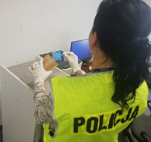 policjantka w kamizelce z napisem policja podczas zabezpieczania materiału biologicznego od podejrzanego