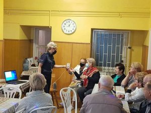 Dzielnicowa prezentuje seniorom zawartość walizki edukacyjnej