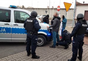 Policjanci przeszukują jednego z demonstrujących przed aresztem śledczym