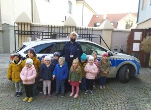 zdjęcie przedstawia grupę przedszkolaków na tle policyjnego radiowozu. Wśród nich stoi dzielnicowa