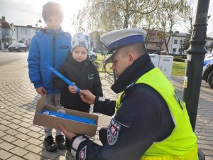 policjant przekazujący elementy odblaskowe chłopcu