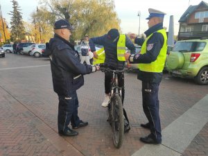 policjanci przekazują kamizelkę odblaskową młodemu rowerzyście