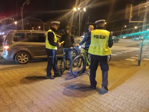 policjanci podczas przekazania elementów odblaskowym trzem młodym cyklistom