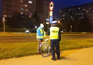 policjant przekazujący kamizelkę z elementami odblaskowymi rowerzystce